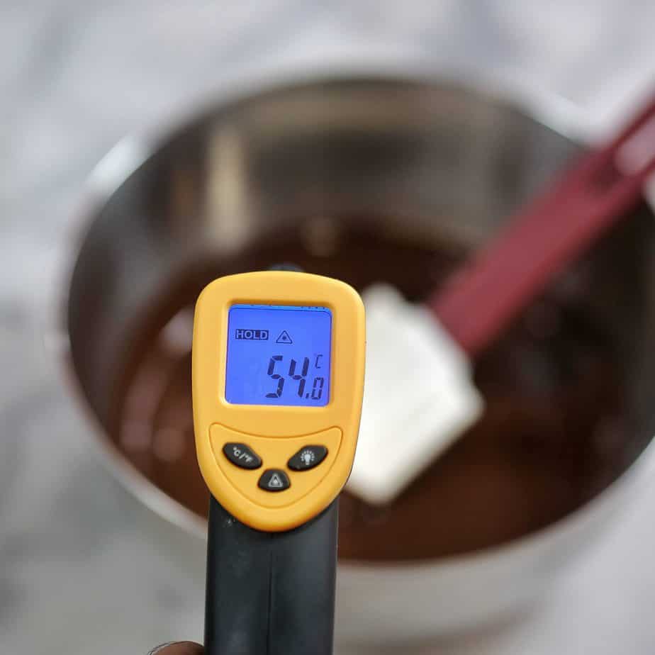 le chocolat fondu est mesuré avec un thermomètre pour vérifier la